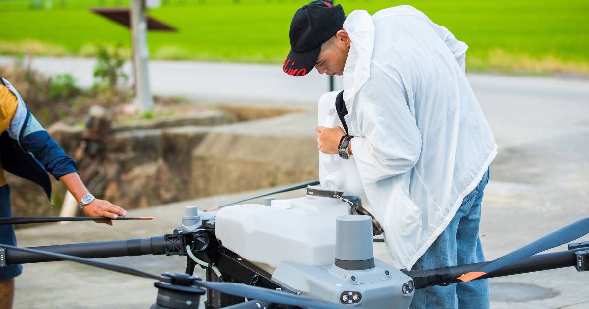 Homem abastecendo o tanque do drone DJI Agras T50 para pulverização